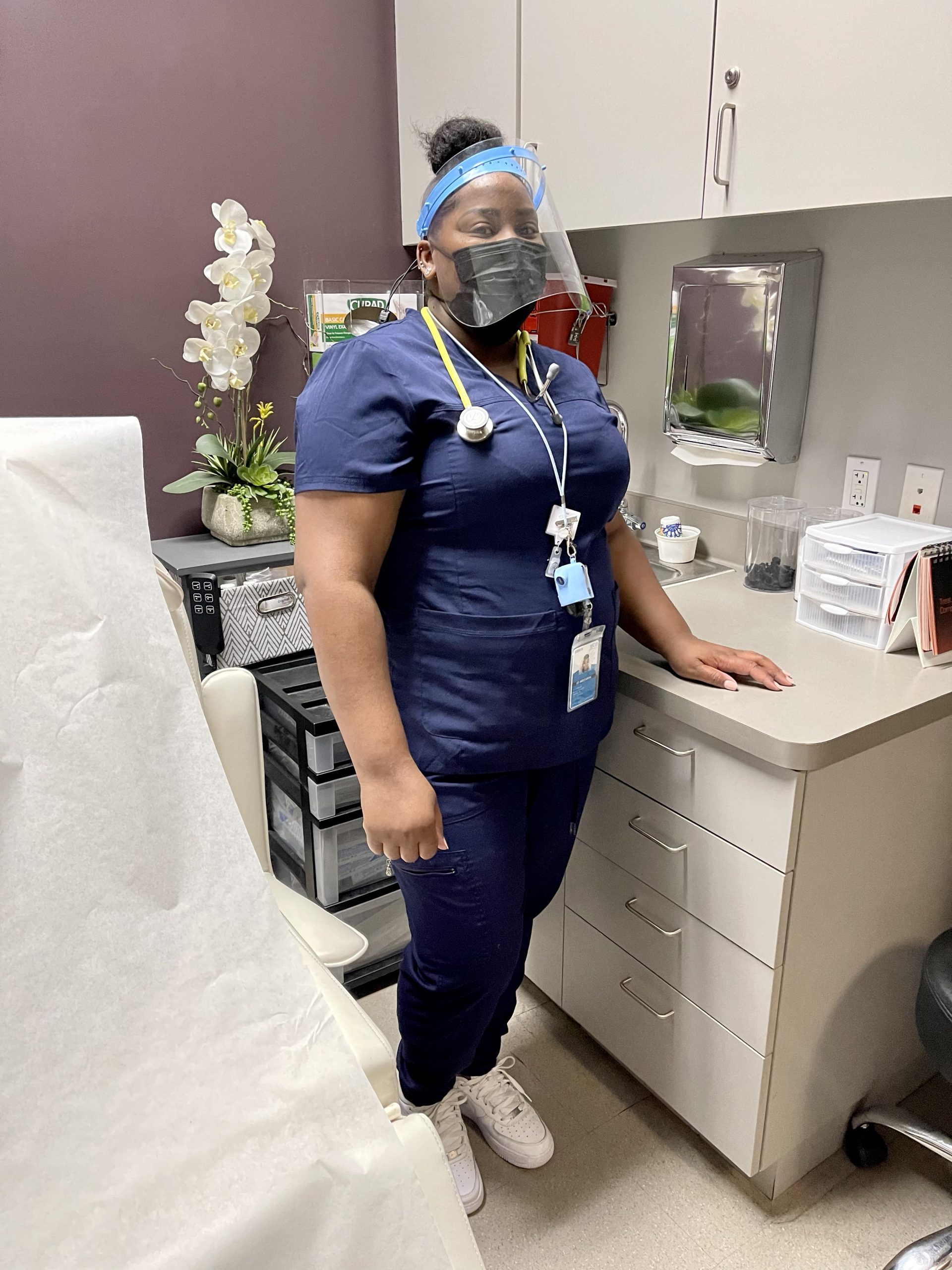 woman in mask and scrubs in office
